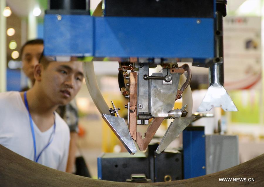 Visitors look at a smart device displayed at the 17th China West International Equipment Manufacturing Exposition (CWIEME) in Chengdu, capital of southwest China's Sichuan Province, July 18, 2013. The three-day CWIEME kicked off Thursday at Chengdu Century City New International Conference & Exhibition Center. (Xinhua/Hu Jiayan)