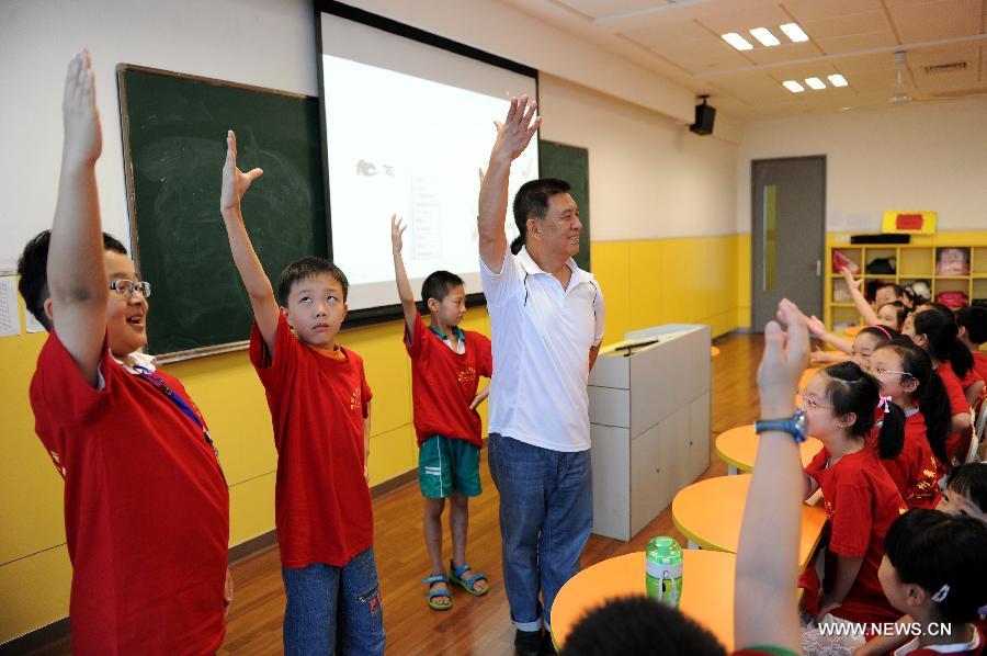 Zhang Liehu, a national first-class performer, guides children to experience Zuo, a performance of Peking Opera, at a lecture about Peking Opera in a youth and children's development center in Hangzhou, east China's Zhejiang Province, July 18, 2013. The lecture is held to enrich children's life during summer vacation.(Xinhua/Ju Huanzong)  