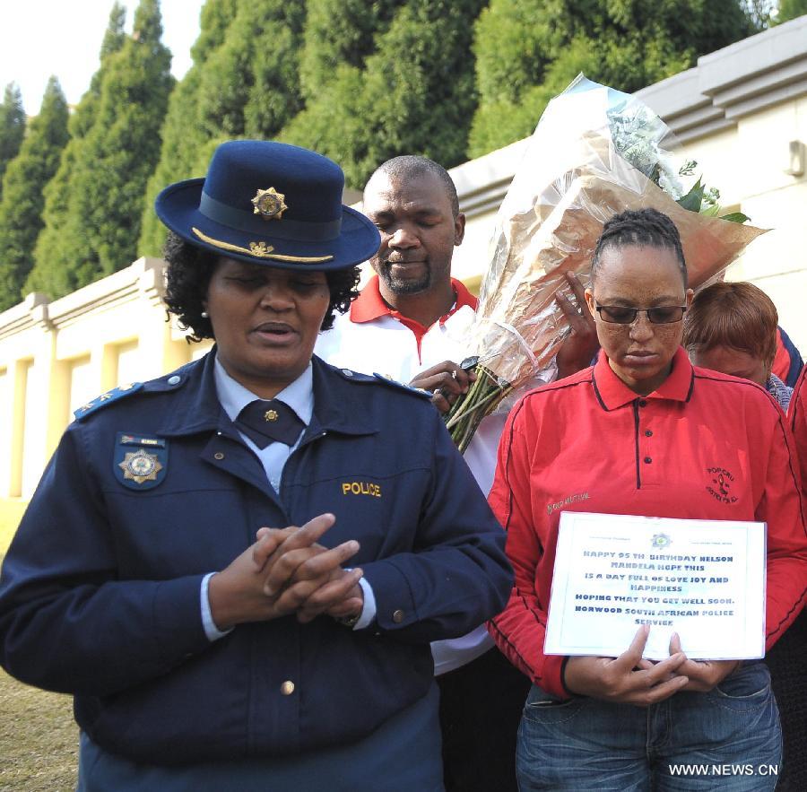 People pray for Mandela outside his house in Johannesburg, South Africa, on July 18, 2013. South African former president Mandela is steadily improving, according to the Presidency website update released on Thursday. "Madiba remains in hospital in Pretoria but his doctors have confirmed that his health is steadily improving," said the statement. President Jacob Zuma wished the founding father of the nation a happy 95th birthday. (Xinhua/Li Qihua)