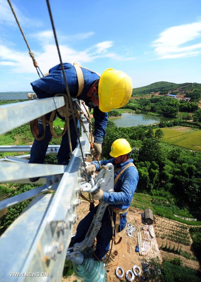 Power grid workers construct a 500kv transmission line at the height of more than 60 meters at Guquan Town in Xuancheng City, east China's Anhui Province, July 18, 2013. (Xinhua/Zheng Xianlie)