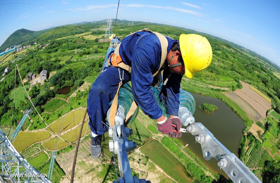 A power grid worker constructs a 500kv transmission line at the height of more than 60 meters at Guquan Town in Xuancheng City, east China's Anhui Province, July 18, 2013. (Xinhua/Zheng Xianlie)