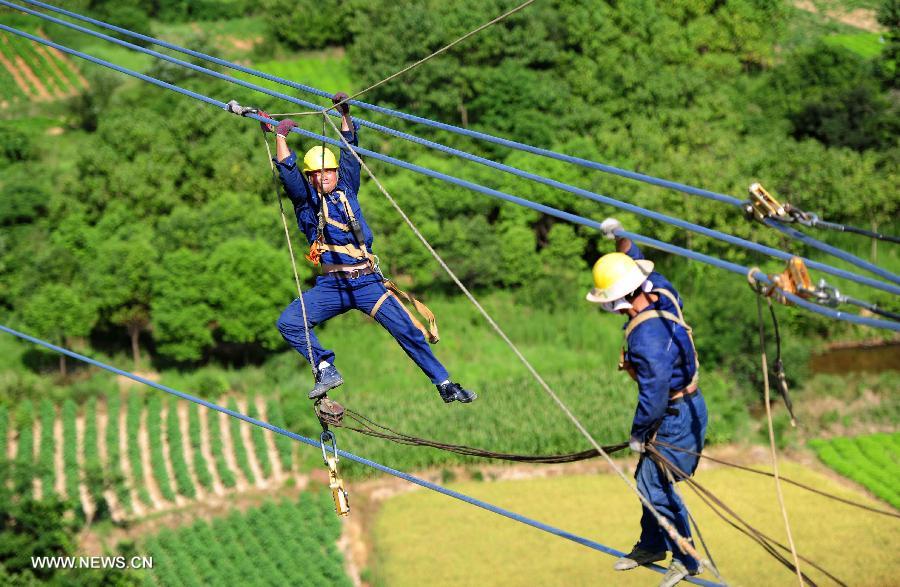 Power grid workers construct a 500kv transmission line at the height of more than 60 meters at Guquan Town in Xuancheng City, east China's Anhui Province, July 18, 2013. (Xinhua/Zheng Xianlie)