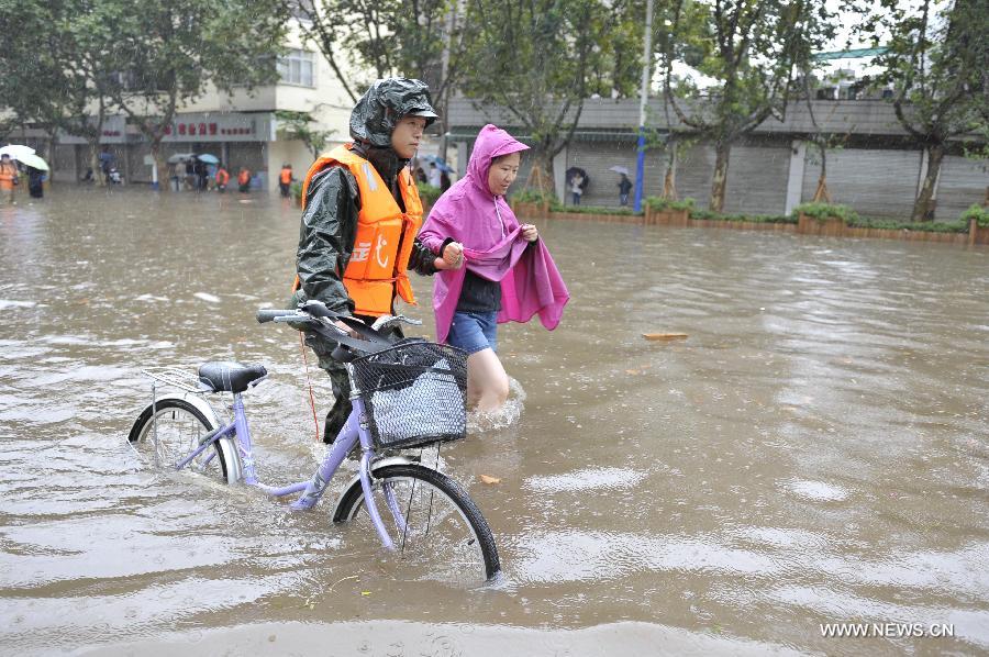 A rescuer helps a citizen pass the flooded Chuanjin Road in Kunming, capital of southwest China's Yunnan Province, July 19, 2013. Kunming was hit by a heavy rainstorm from Thursday to Friday. Kunming's meteorologic center on Friday issued a blue alert for rainstorm. (Xinhua/Hao Yaxin)