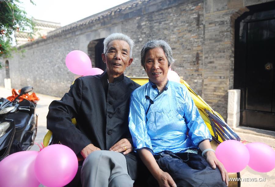 An elder couple poses for a photo in the Yangzhou Ancient Street in Yangzhou of east China's Jiangsu Province, July 18, 2013. Three elder couples took rickshaws to have a sightseeing around the Yangzhou Ancient Street in celebration of their Golden Wedding Anniversary. (Xinhua/Si Xinli)