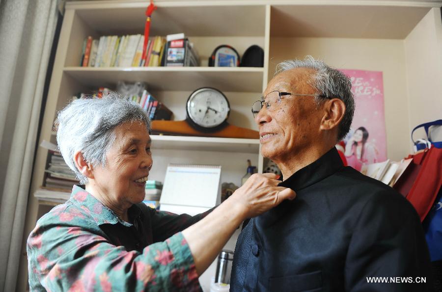 An elder woman helps her husband adjust the clothes in Yangzhou of east China's Jiangsu Province, July 18, 2013. Three elder couples took rickshaws to have a sightseeing around the Yangzhou Ancient Street in celebration of their Golden Wedding Anniversary. (Xinhua/Si Xinli)