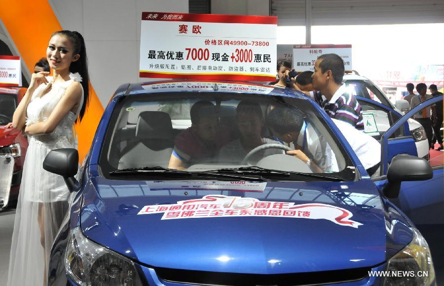 Consumers watch a vehicle at the 5th Huhhot International Auto Exhibition in Huhhot, north China's Inner Mongolia Autonomous Region, July 19, 2013. Some 400 vehicles from more than 70 enterprises and brands were taken to the five-day exhibition which kicked off on Friday. (Xinhua/Liu Yide)