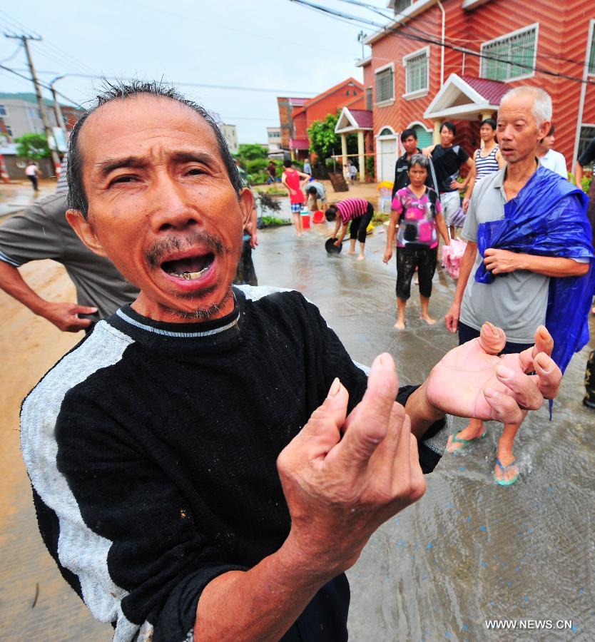 A local resident describes damages caused by the flood in Shenwo Village of Gangwei Township in Longhai of Zhangzhou City, southeast China's Fujian Province, July 19, 2013. Tropical storm Cimaron made its landfall in Fujian Thursday evening, bringing heavy rain and strong gales to southern part of the province. Xiamen, Zhangzhou, Quanzhou and Putian were severely affected by the storm, with the rainfall in some regions like Longhai reaching 520 millimeters on Friday. About 123,000 residents were afflicted by the storm and no casualties have been reported yet. (Xinhua/Wei Peiquan) 