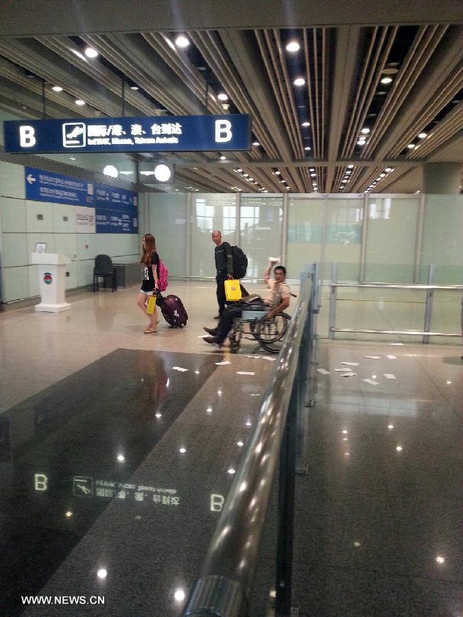 Photo taken on July 20, 2013 with a cellphone shows Ji Zhongxing (man on the wheelchair), suspect of an explosion at Terminal 3 of the Beijing Capital International Airport in Beijing, capital of China. Ji, a 34-year-old from Heze City of east China's Shandong Province, set off a home-made explosive device outside the arrivals exit of the Terminal 3 at around 6:24 p.m. Saturday after he was stopped from handing out leaflets to get attention to his complaints, an initial police investigation showed. Ji suffered no life-threatening injuries and no other injuries were caused. The police cordon at the arrivals exit has been removed, and the airport has begun to resume normal order. (Xinhua)