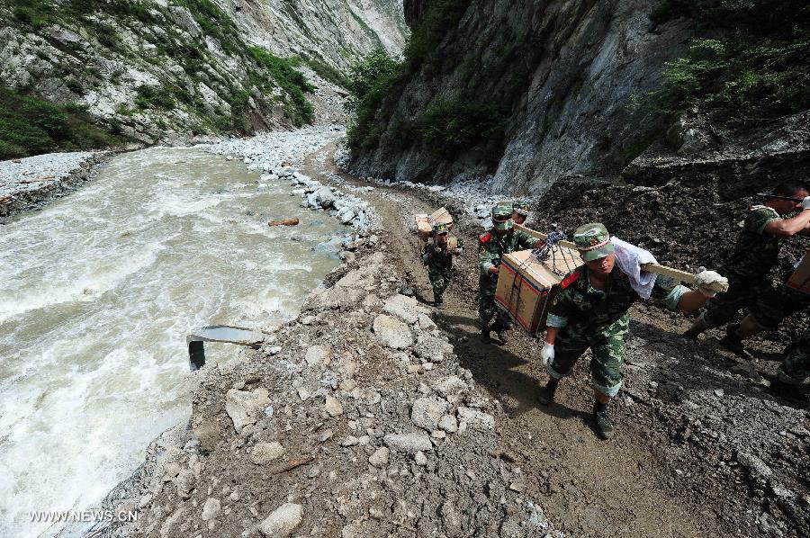 Villagers are evacuated on the restored road in Caopo Township of Wenchuan County, southwest China's Sichuan Province, July 20, 2013. The road lingking Caopo Township and outside which was badly damaged by previous mud-rock flow has been reopened on Saturday, which will facilitate future rescue work in the town.(Xinhua/He Haiyang) 