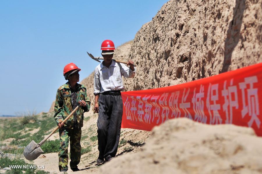 Two workers walk past the Great Wall in Shandan County, northwest China's Gansu Province, July 19, 2013. This year, the local authorities has allocated more than 30 million yuan (about 4.89 million U.S. dollars) for the protection of the Great Wall in Shandan County, which was built in the Ming Dynasty (1368-1644) and has a length of 88 kilometers. (Xinhua/Chen Bin)