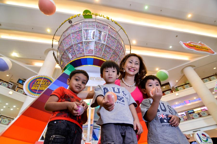 Three children shows capsules from a capsule vending machine which sets a Guinness World Record for the world's largest one, at a shopping mall in Kuala Lumpur, capital of Malaysia, on July 20, 2013. The machine which can contain 125,000 capsules will be used here for four months. (Xinhua/Chong Voon Chung) 