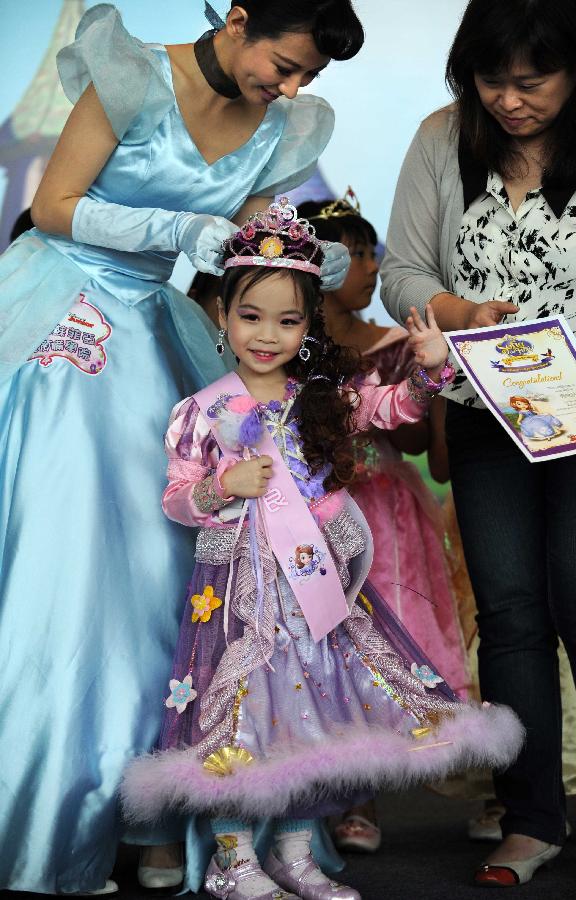 Actress Annie Lau (L)crowns a little girl who wins a certificate of achievement in the final of "Sofia the First" Little Princess Recruitment in south China's Hong Kong, July 21, 2013. "Sofia the First" is a television cartoon series produced by Disney. In total 25 little girls competed during the final recruitment organized by Disney Junior channel. (Xinhua/Zhao Yusi)