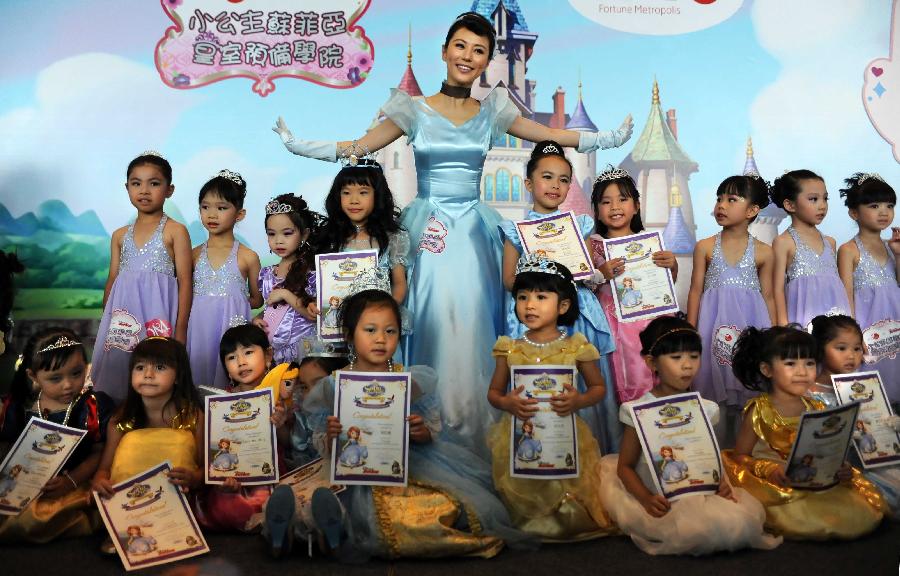 Actress Annie Lau (C) poses for a group picture with little girls participating in the final of "Sofia the First" Little Princess Recruitment in south China's Hong Kong, July 21, 2013. "Sofia the First" is a television cartoon series produced by Disney. In total 25 little girls competed during the final recruitment organized by Disney Junior channel. (Xinhua/Zhao Yusi)