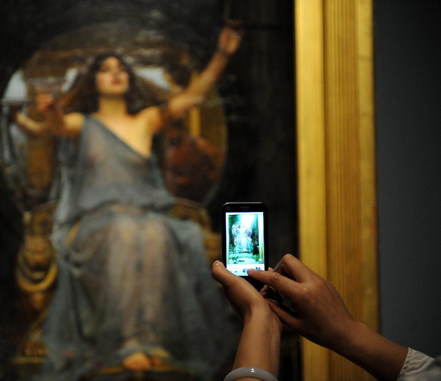 A woman takes pictures of a painting with her cellphone at an exhibition displaying works of art from public collection in northwest England in Zhengzhou, capital of central China's Henan Province, July 21, 2013. Many local citizens spent their weekends by visiting the exhibition, which lasts from June 25, 2013 to Aug. 9, 2013 at Henan Museum. (Xinhua/Li Bo)