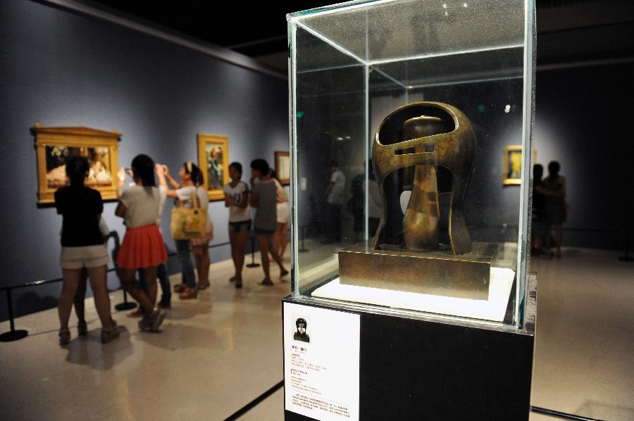 Visitors take pictures of paintings at an exhibition displaying works of art from public collection in northwest England in Zhengzhou, capital of central China's Henan Province, July 21, 2013. Many local citizens spent their weekends by visiting the exhibition, which lasts from June 25, 2013 to Aug. 9, 2013 at Henan Museum. (Xinhua/Li Bo)