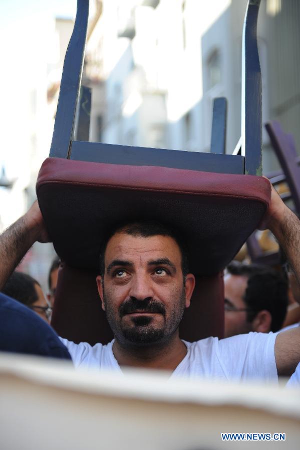 A man carries a table in demonstration in Istanbul on July 21, 2013. Around two thousand people carrying tables and chairs gathered on the Istiklal Avenue, staged a demonstration on Sunday to protest against the municipality's ban on outdoor sitting. The protest marks the second anniversary of the ban on July 21. In 2011 municipality officials removed the street-side tables around Beyoglu's main thoroughfare Istiklal and the upscale Cihangir neighborhood which fueled public outrage. (Xinhua/Lu Zhe) 