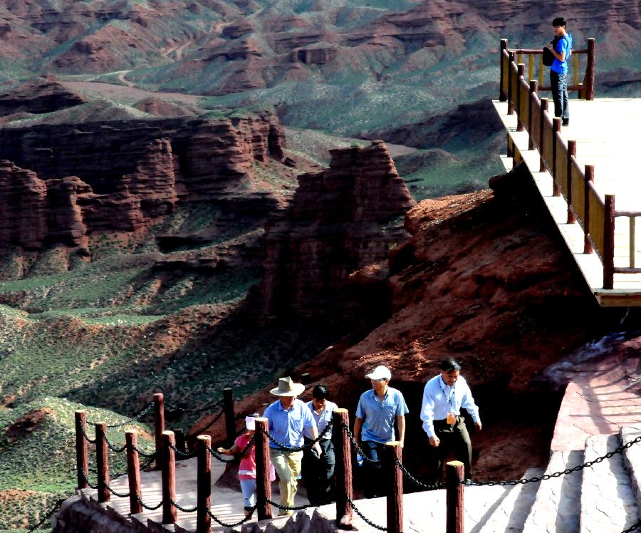 Tourists view the scenery of Danxia landform at Pingshan Lake scenic area in Zhangye City, northwest China's Gansu Province, July 20, 2013. Danxia, which means "rosy cloud", is a special landform formed from reddish sandstone that has been eroded over time into a series of mountains surrounded by curvaceous cliffs and many unusual rock formations. (Xinhua/Wang Jiang)