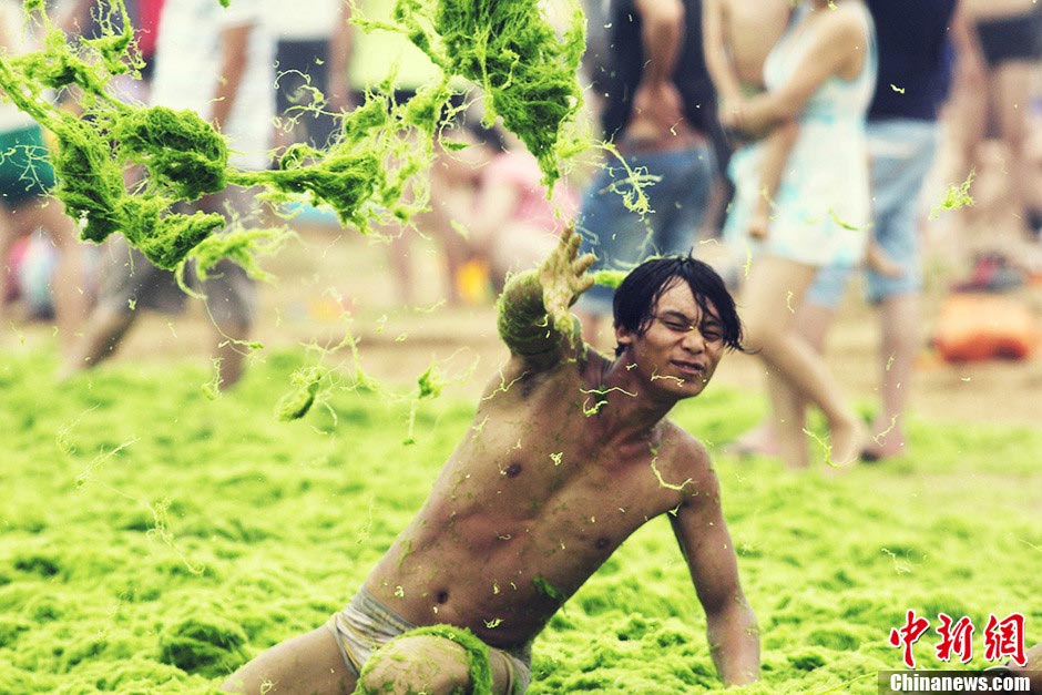 Several boys play war games with green algae on the beach in Qingdao, east China's Shandong province, July 18, 2013. (CNS/Xue Hun)
