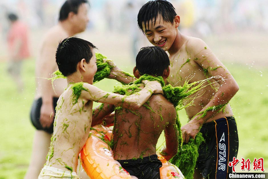 Several boys play war games with green algae on the beach in Qingdao, east China's Shandong province, July 18, 2013. (CNS/Xue Hun)