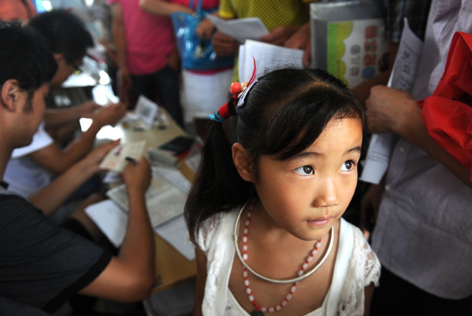 Zhang Jiahui waits for school registration in Furong Primary School in Hefei, capital of east China's Anhui province on July 16, 2013. The happiest thing for 6-year-old Zhang Jiahui in this summer was to leave her hometown - a small village- and move to the city to live with her parents who worked in Hefei. Zhang thus bid farewell to the life of left-behind child. (Xinhua/Liu Xijun)