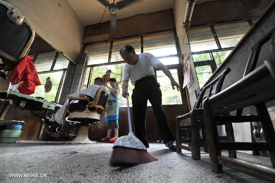 Ou Shubin (C) sweeps the floor at his old-fashioned barbershop at No. 76, Meihua Road in Ningxiang County, central China's Hunan Province, July 21, 2013. Affectionately known as Ou Die, or Daddy Ou in the neighborhood, the 78-year-old barber has been in the business for 66 years and run the current shop for 33 years, offering traditional services to old customers. (Xinhua/Long Hongtao) 