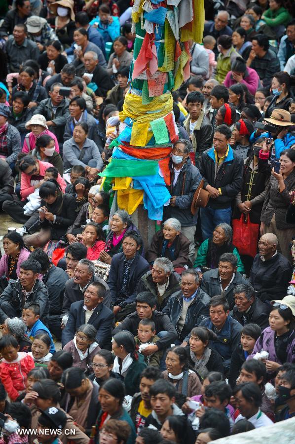 Devotees worship a huge Buddha portrait after unfolding it during the annual religious ritual in the Gandan Temple in Lhasa, capital of southwest China's Tibet Autonomous Region, July 22, 2013. Founded in 1409 by followers of Zong Kaba, founder of the Yellow Sect of Tibetan Buddhism, the Gandan Temple is the oldest among lamaseries of the Yellow Sect. (Xinhua/Purbu Zhaxi)