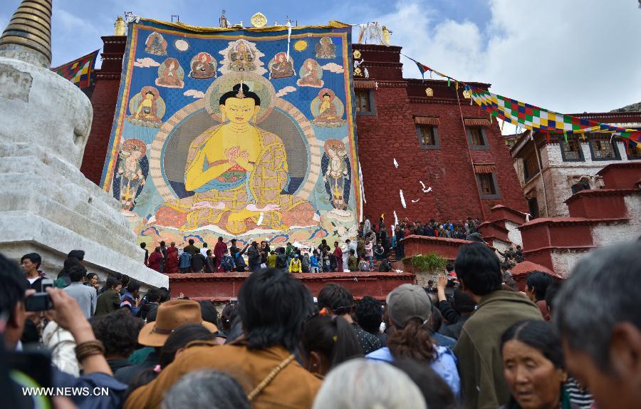 Devotees worship a huge Buddha portrait after unfolding it during the annual religious ritual in the Gandan Temple in Lhasa, capital of southwest China's Tibet Autonomous Region, July 22, 2013. Founded in 1409 by followers of Zong Kaba, founder of the Yellow Sect of Tibetan Buddhism, the Gandan Temple is the oldest among lamaseries of the Yellow Sect. (Xinhua/Purbu Zhaxi)