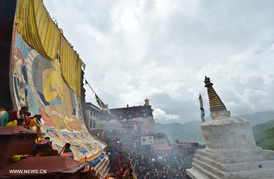 Devotees worship a huge Buddha portrait after unfolding it during the annual religious ritual in the Gandan Temple in Lhasa, capital of southwest China's Tibet Autonomous Region, July 22, 2013. Founded in 1409 by followers of Zong Kaba, founder of the Yellow Sect of Tibetan Buddhism, the Gandan Temple is the oldest among lamaseries of the Yellow Sect. (Xinhua/Purbu Zhaxi)