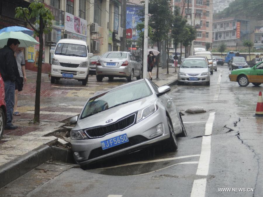 A car is trapped on a collapsed road in Yan'an City, northwest China's Shaanxi Province, July 22, 2013. Houses and roads collapsed, water level of river rose significantly over the past days due to continuous rainfalls in the region. (Xinhua/Gao Wangqing) 