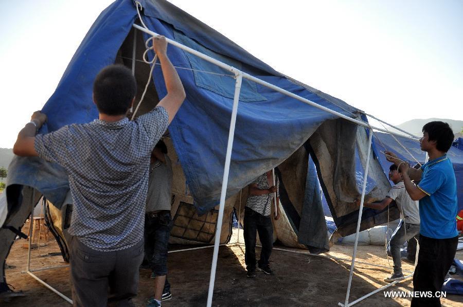 People put up a tent at a temporary settlement at quake-hit Majiagou Village of Minxian County, northwest China's Gansu Province, July 22, 2013. The death toll has climbed to 89 in the 6.6-magnitude earthquake which jolted a juncture region of Minxian County and Zhangxian County in Dingxi City Monday morning. (Xinhua/Guo Gang)