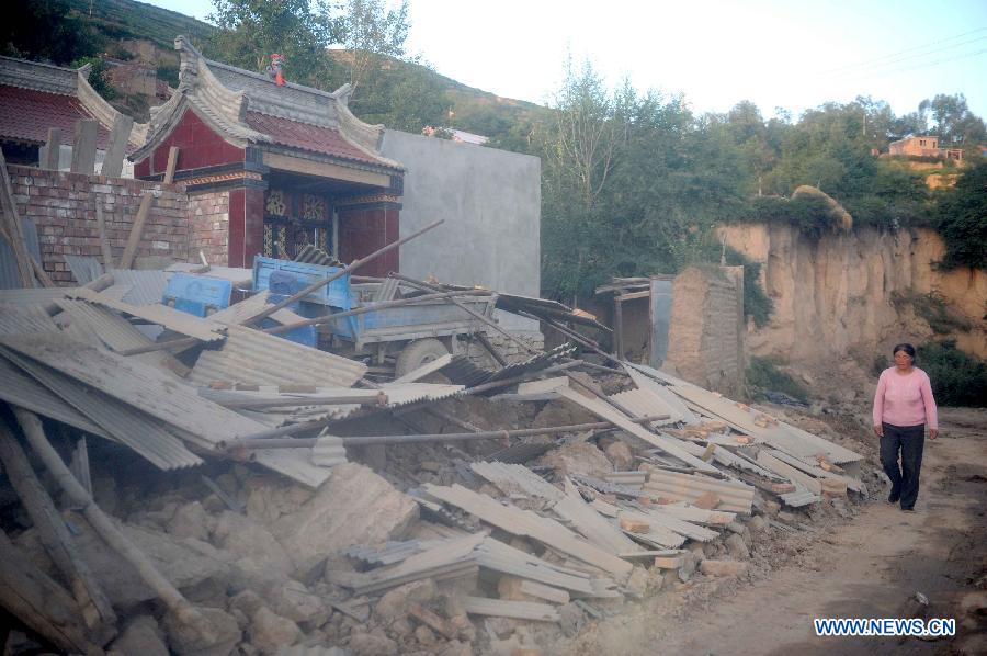 A villager walks past a collapsed house after a quake in Meichuan Town, Minxian County, northwest China's Gansu Province, July 22, 2013. A 6.6-magnitude quake jolted the border of Minxian and Zhangxian counties in Gansu at 7:45 a.m. on Monday. (Xinhua/Luo Xiaoguang)