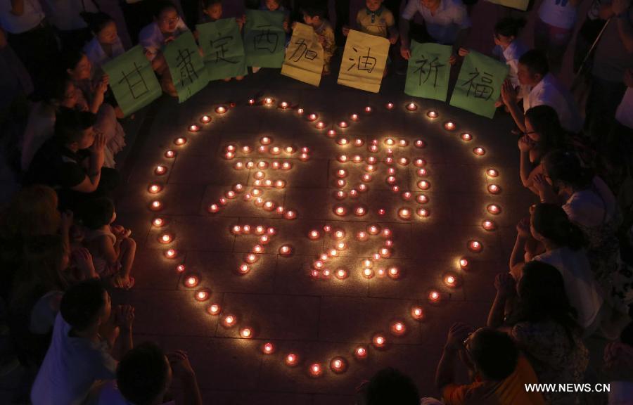 People pray for those affected by the earthquake hitting northwest China's Gansu Province, in Loudi City, central China's Hubei Province, July 22, 2013. The death toll has climbed to 89 in the 6.6-magnitude earthquake which jolted a juncture region of Minxian County and Zhangxian County in Dingxi City of Gansu Province Monday morning. (Xinhua/Guo Guoquan)