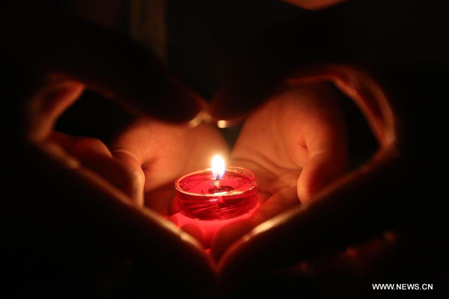 A volunteer holds candles as they pray for the residents and victims of quake-hit Dingxi City in northwest China's Gansu Province, in Loudi City, central China's Hunan Province, July 22, 2013. A 6.6-magnitude earthquake jolted a juncture region of Minxian County and Zhangxian County in Dingxi City Monday morning, leaving 89 people dead. (Xinhua/Guo Guoquan)