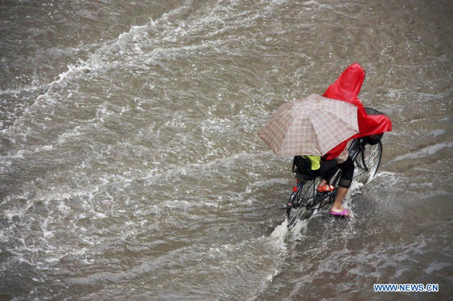 Citizens ride on a flooded road in Liaocheng City, east China's Shandong Province, July 23, 2013. Heavy rainfall hit parts of the province in these two days. (Xinhua/Kong Xiaozheng)