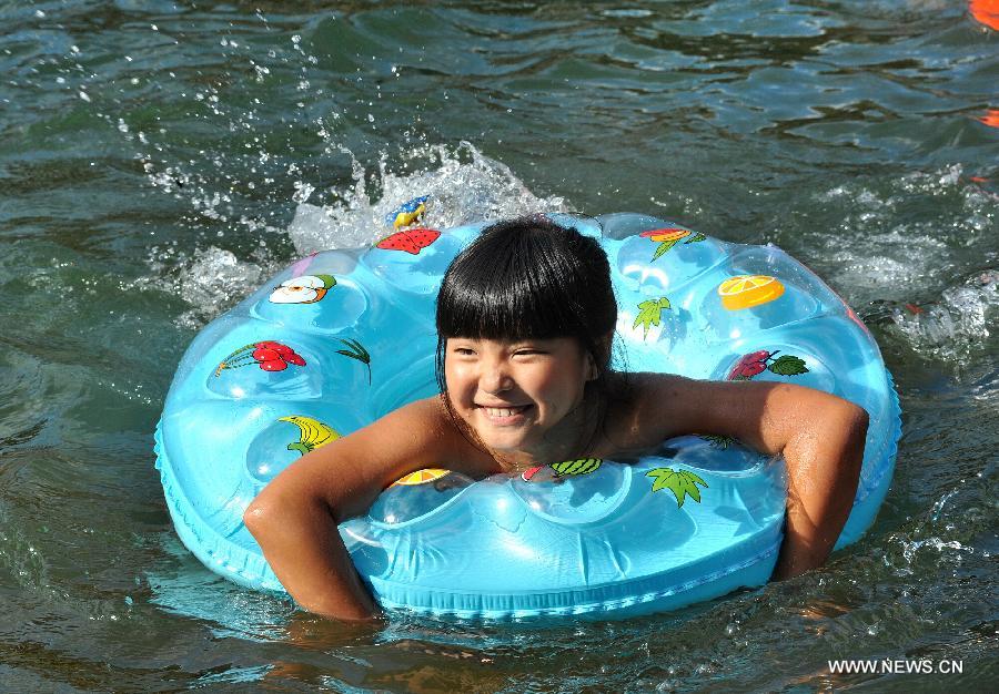 A girl enjoys coolness in the Tuojiang River in Fenghuang ancient town, central China's Hunan Province, July 23, 2013. The provincial meteorological observatory issued an orange alert for high temperatures in Hunan, estimating that the highest temperature will reach 37 degrees Celsius in most pasts of the province. (Xinhua/Long Hongtao)