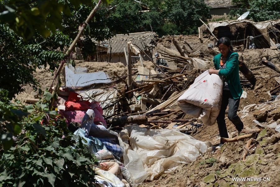 A villager searches for available articles at her quake-hit home in Yongguang Village of Minxian County, northwest China's Gansu Province, July 23, 2013. The death toll has climbed to 94 in the 6.6-magnitude earthquake which jolted a juncture region of Minxian County and Zhangxian County in Dingxi City Monday morning. (Xinhua/Liu Xiao)