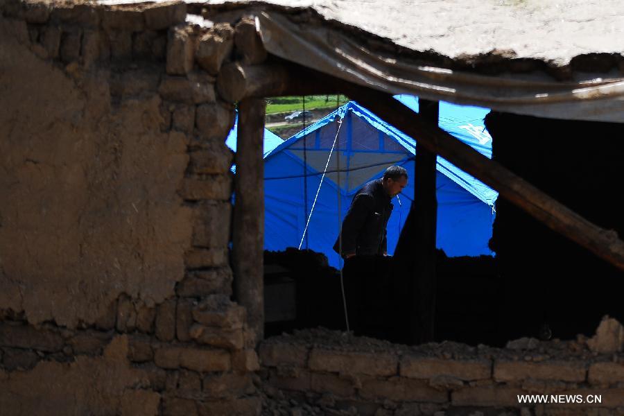 A villager searches for available articles at his quake-hit home in Yongxing Village of Minxian County, northwest China's Gansu Province, July 23, 2013. The death toll has climbed to 94 in the 6.6-magnitude earthquake which jolted a juncture region of Minxian County and Zhangxian County in Dingxi City Monday morning. (Xinhua/Liu Xiao)