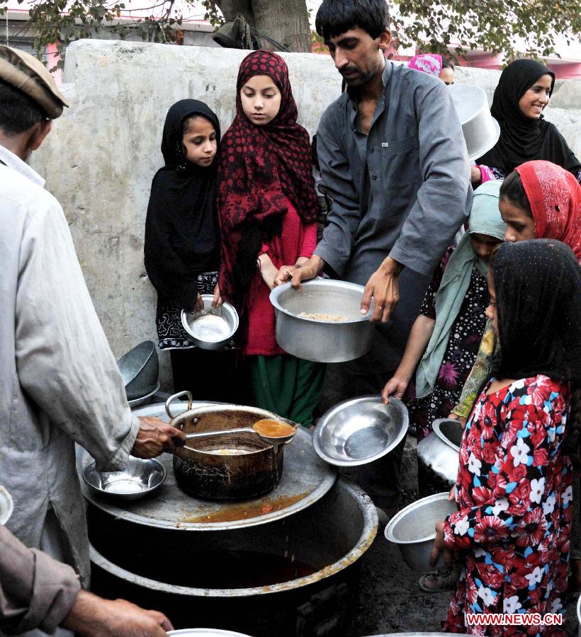 Afghan children receive food donated by rich people during holy month of Ramadan in Nangarhar province in eastern Afghanistan on July 23, 2013. (Xinhua/Tahir Saf)