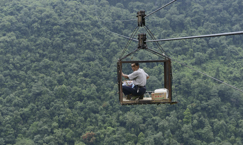 A man uses a ropeway to go over across a valley on July 23, 2013 in Central China's Hubei province. The 1000-meter ropeway has been the only shortcut for 196 Yushan villagers to get in and out of their home area, surrounded by mountains on three sides, since it was established in 1997. The village is 150 kilometers southeast of Hefeng county, Hubei province.(Photo/Xinhua)