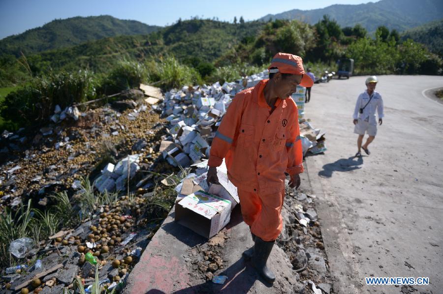 A highway worker cleans the accident site where a vehicle overturned on a provincial highway in Nanfeng County, east China's Jiangxi Province, July 24, 2013. The accident that occurred late Tuesday has left 16 people dead and 10 others injured, local authorities said early Wednesday. Fifteen people were killed on the spot, and one died after medical treatment failed. Ten people were treated in local hospitals. (Xinhua/Zhou Mi)