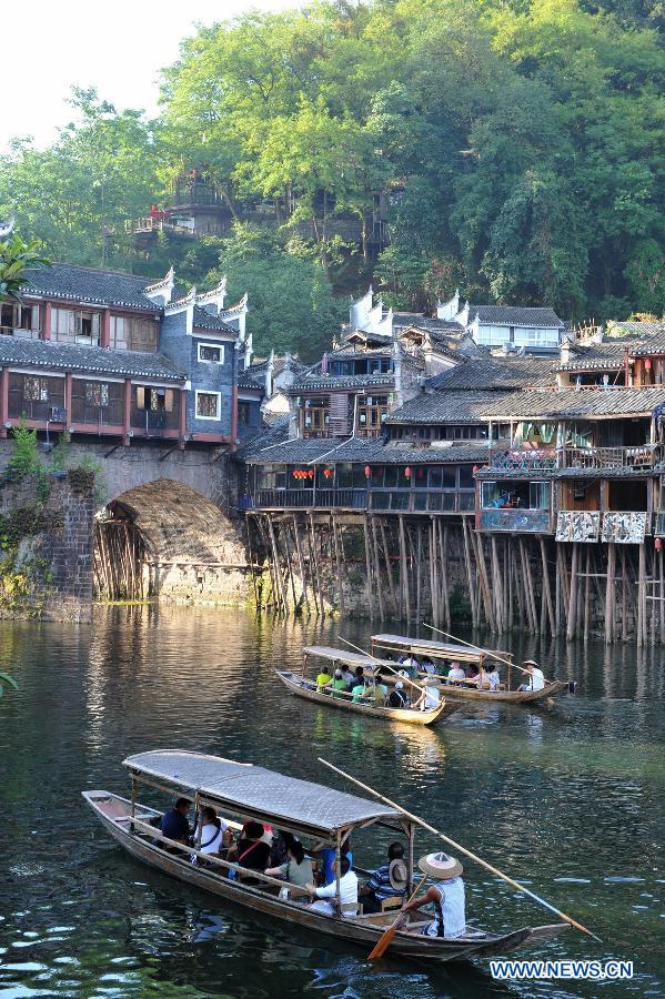 Tourists enjoy the scenery in boats on the Tuojiang River in the ancient town of Fenghuang in Fenghuang County of Xiangxi Tu and Miao Autonomous Prefecture, central China's Hunan Province, July 23, 2013. The tourist resort witnessed a travel peak in July, attracting 417,400 visitors till July 22, increasing by 28.79 percent year on year. (Xinhua/Long Hongtao)