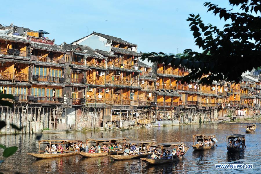 Tourists enjoy the scenery in boats on the Tuojiang River in the ancient town of Fenghuang in Fenghuang County of Xiangxi Tu and Miao Autonomous Prefecture, central China's Hunan Province, July 23, 2013. The tourist resort witnessed a travel peak in July, attracting 417,400 visitors till July 22, increasing by 28.79 percent year on year. (Xinhua/Long Hongtao)