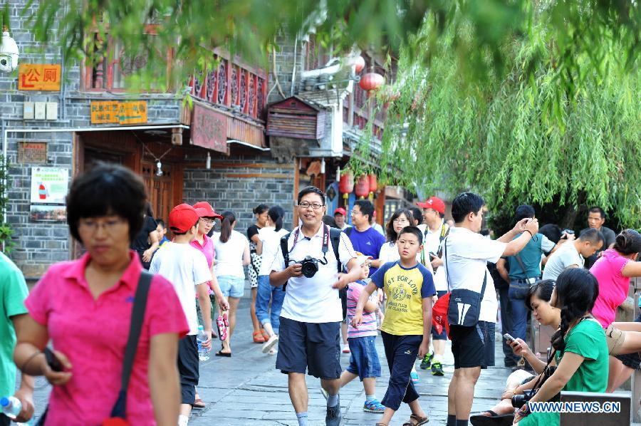 Tourists are seen in the ancient town of Fenghuang in Fenghuang County of Xiangxi Tu and Miao Autonomous Prefecture, central China's Hunan Province, July 23, 2013. The tourist resort witnessed a travel peak in July, attracting 417,400 visitors till July 22, increasing by 28.79 percent year on year. (Xinhua/Long Hongtao)