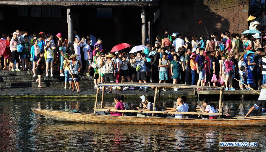 Tourists wait to board boats beside the Tuojiang River in the ancient town of Fenghuang in Fenghuang County of Xiangxi Tu and Miao Autonomous Prefecture, central China's Hunan Province, July 23, 2013. The tourist resort witnessed a travel peak in July, attracting 417,400 visitors till July 22, increasing by 28.79 percent year on year. (Xinhua/Long Hongtao)