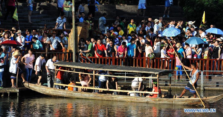 Tourists wait to board boats beside the Tuojiang River in the ancient town of Fenghuang in Fenghuang County of Xiangxi Tu and Miao Autonomous Prefecture, central China's Hunan Province, July 23, 2013. The tourist resort witnessed a travel peak in July, attracting 417,400 visitors till July 22, increasing by 28.79 percent year on year. (Xinhua/Long Hongtao)