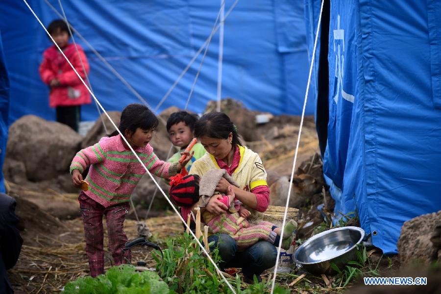 A villager washes her child's face in quake-hit Yongxing Village of Minxian County, northwest China's Gansu Province, July 24, 2013. The death toll has climbed to 95 in the 6.6-magnitude earthquake which jolted a juncture region of Minxian County and Zhangxian County in Dingxi City Monday morning. (Xinhua/Zhang Meng)