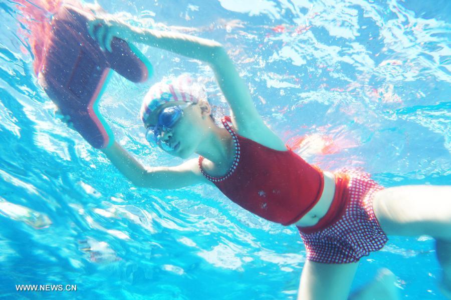 Photo taken under water on July 24, 2013 shows a child swimming in an outdoor swimming pool of a park in Hangzhou, capital of east China's Zhejiang Province. Local meteorological observatory issued a red alert for high temperature, warning that the highest temperature will reach 40.4 degrees Celsius on Wednesday, which also marked the hottest day on record. (Xinhua/Li Zhong)