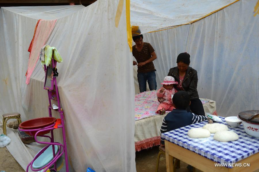 A family rest in a makeshift tent in the quake-hit Majiagou Village, Meichuan Township, Minxian County, northwest China's Gansu Province, July 24, 2013. Due to a lack of tents, almost ten people could share one in the township. The Ministry of Civil Affairs dispatched more tents and quilts to the quake zone of Gansu on Tuesday evening. A 6.6-magnitude quake jolted the juncture of Minxian and Zhangxian counties in the city of Dingxi at 7:45 a.m. Monday, leaving at least 95 people dead as of Tuesday evening. (Xinhua/Jin Liangkuai)