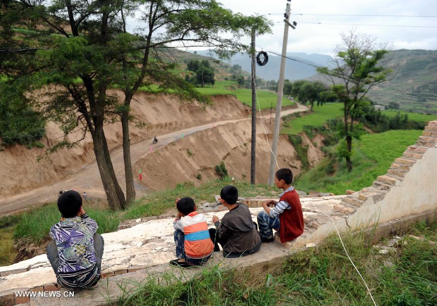 Pupils chat on a damaged wall in the quake-hit Majiagou Village in Meichuan Township, Minxian County, northwest China's Gansu Province, July 24, 2013. Over 360 schools in Gansu's Minxian and Zhangxian counties were destroyed by the 6.6-magnitude quake that occurred on Monday, affecting 77,000 students, according to the local authorities. (Xinhua/Luo Xiaoguang)