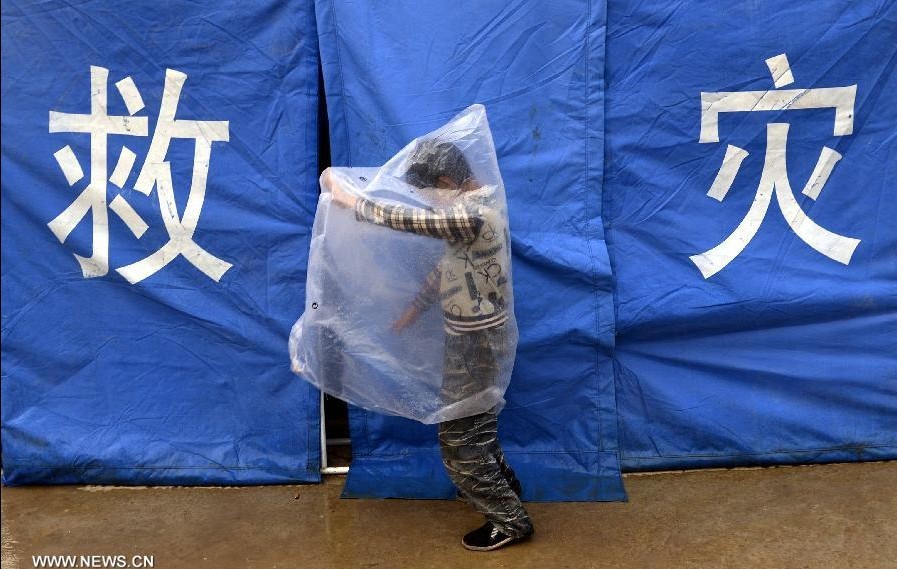 A young boy plays in rain at a temporary settlement for quake-affected people in Qingtu Village of Minxian County, northwest China's Gansu Province, July 24, 2013. A rainfall hit the quake-jolted region in Gansu on Wednesday. The death toll has climbed to 95 in the 6.6-magnitude earthquake which jolted a juncture region of Minxian County and Zhangxian County in Dingxi City Monday morning. (Xinhua/Liu Xiao)